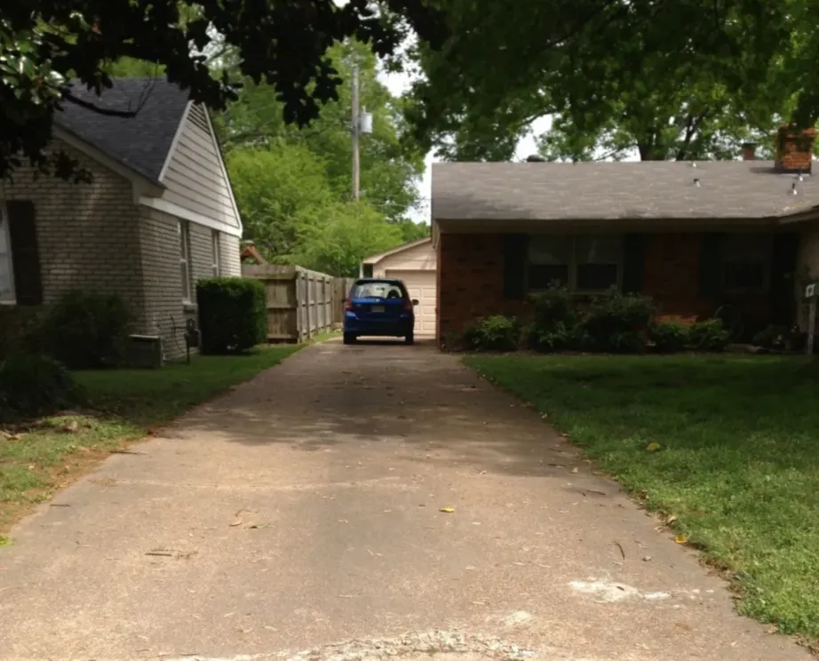 Car between houses under trees