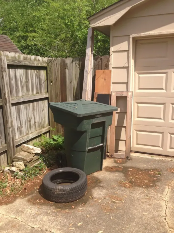 Trash bin near garage with tyre